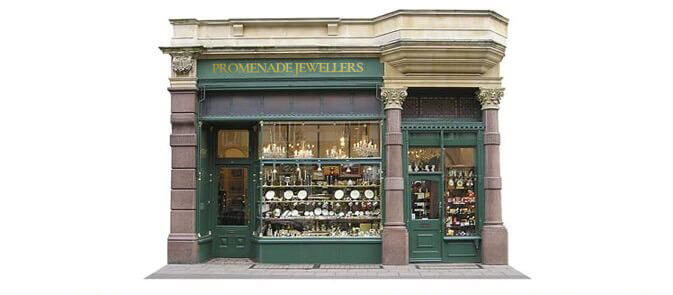 The Promenade Jewellers shopfront today: gold lettering reading PROMENADE JEWELLERS above a green-painted facade with Bath-stone columns, jewellery and silverware in the window
